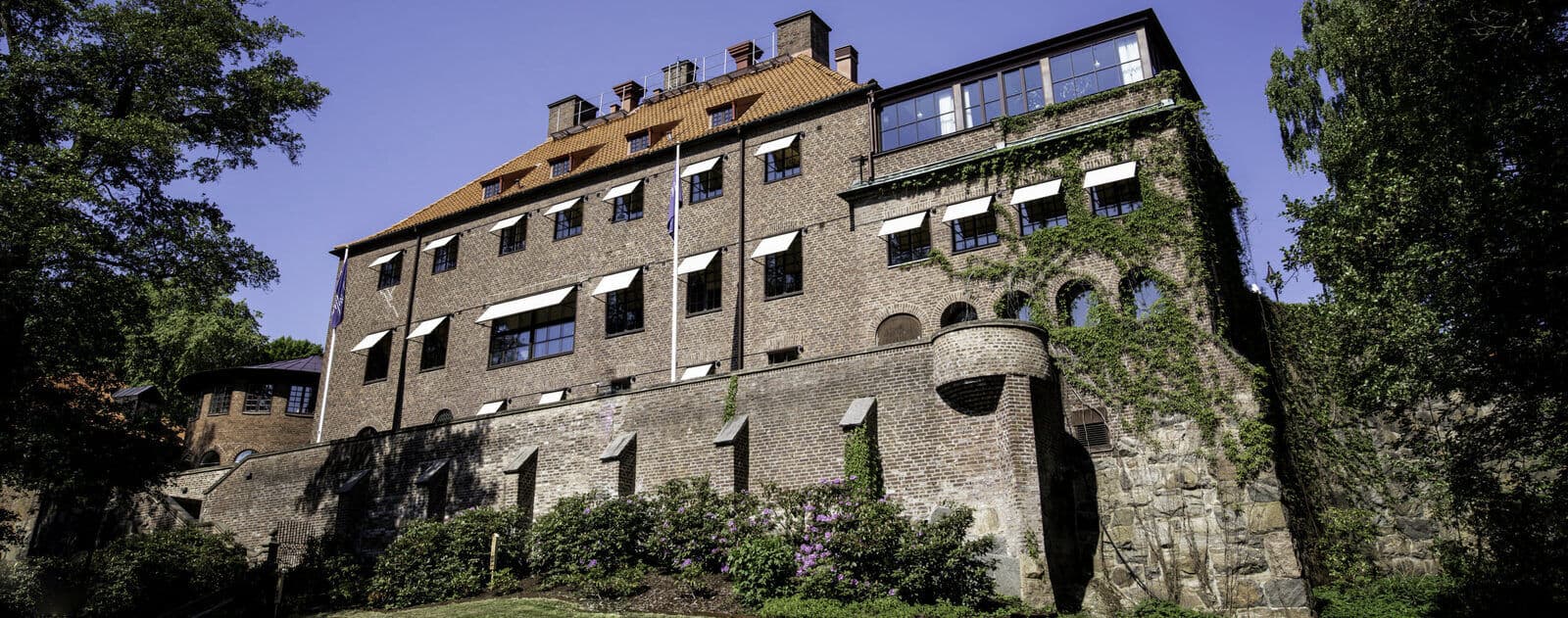 The Auryn office: a brick building with a tiled roof and ivy-covered wall, set above a stone terrace in Gothenburg.
